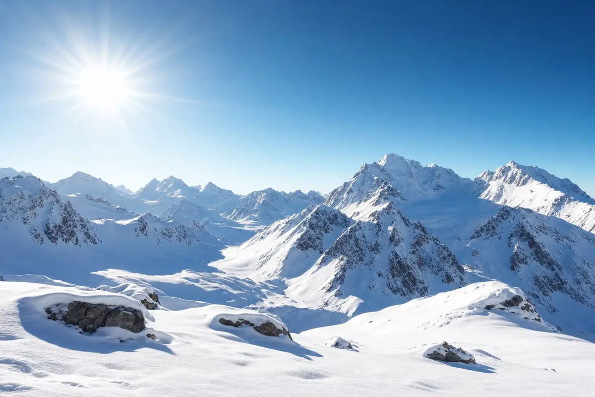A bright sunlit snowy mountain landscape with crisp white snow under a deep blue sky, a classic metering challenge