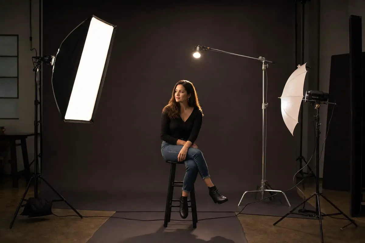 A behind-the-scenes photography studio setup showing key light, fill light, and back light around a portrait subject
